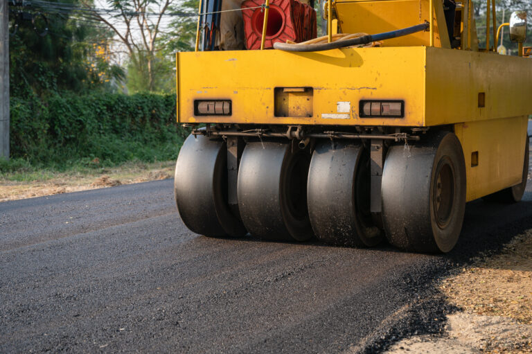 Heavy vibration yellow steamroller or soil compactor working on hot-mix asphalt pavement road at construction site